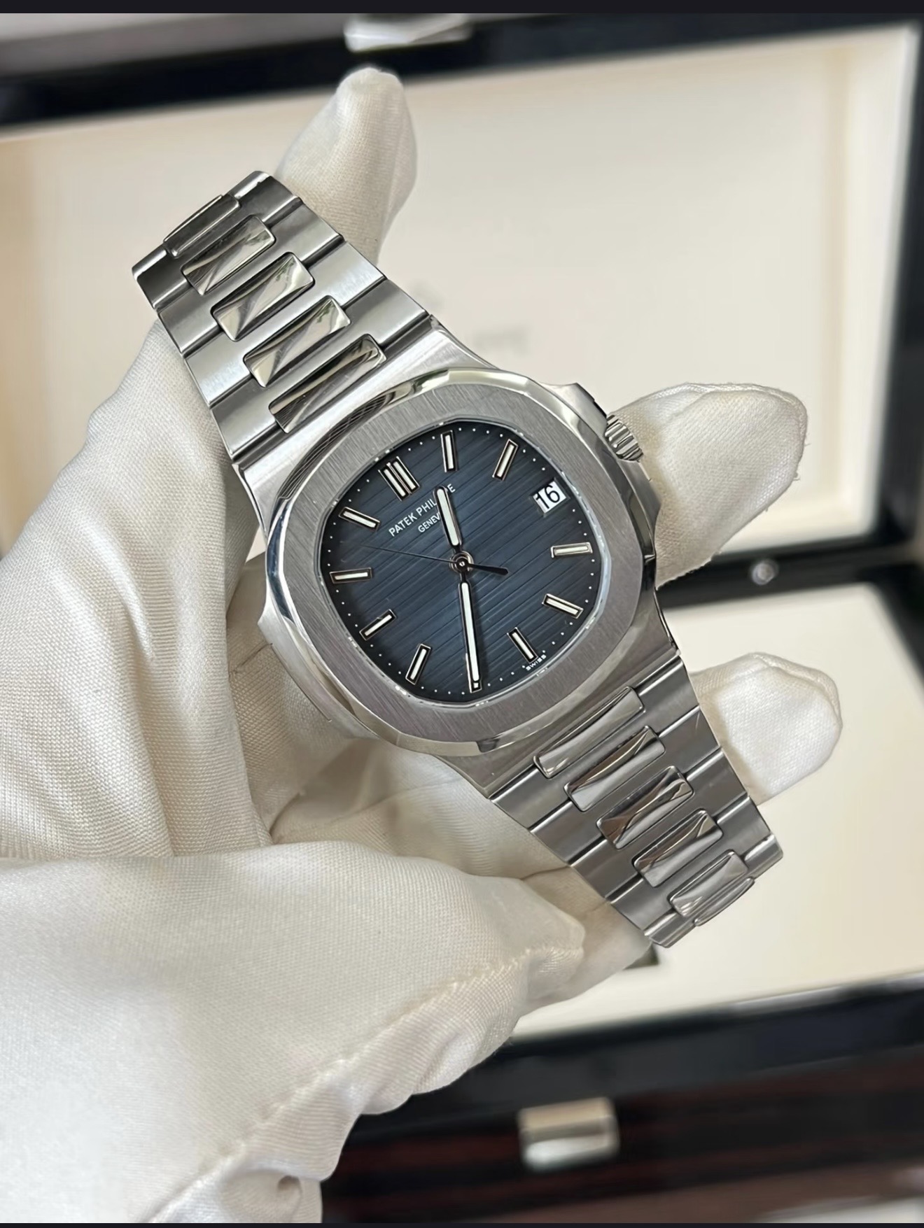 A stainless-steel luxury watch presented by hand in a white glove